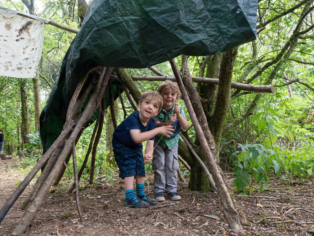 two children under a shelter made of sticks